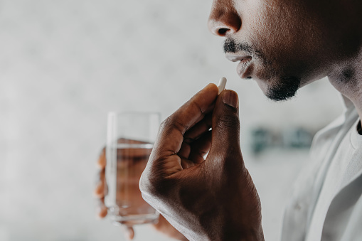 Man taking medicine with glass of water