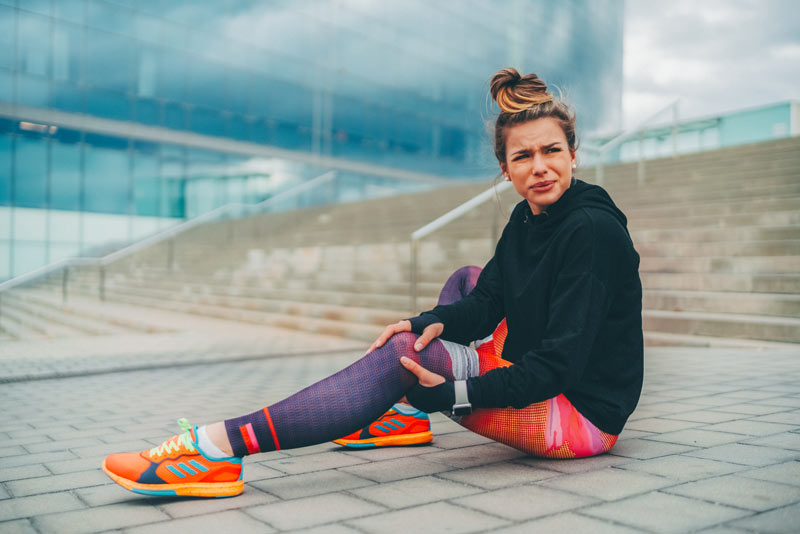 Female runner on ground grabbing knee