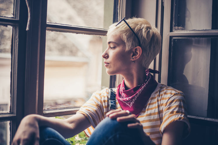 Profile view of blond woman looking through window.