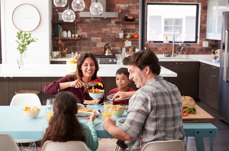 Family with two young children eating breakfast at the kitchen table. 
