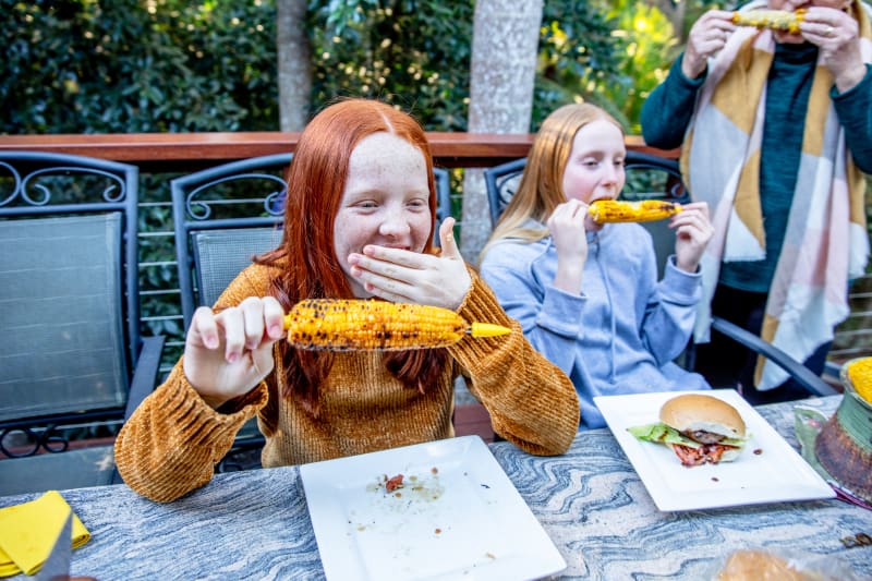 Teenager eating corn on the cob with friends.