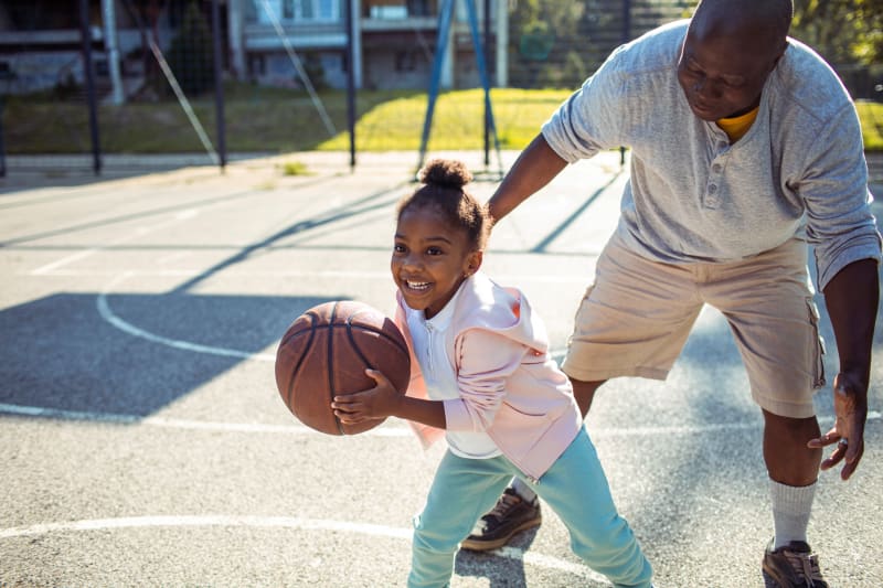 Father playing basketball with young daughter.