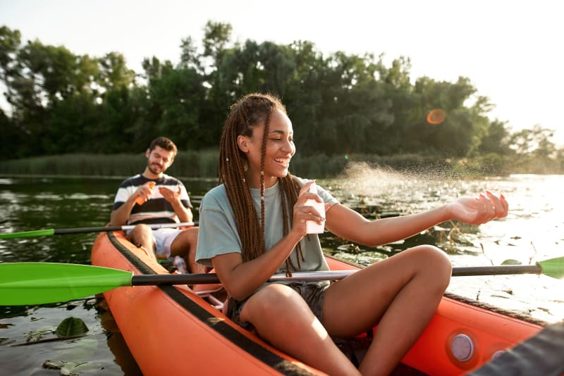 Young woman in kayak applying sunscreen. 