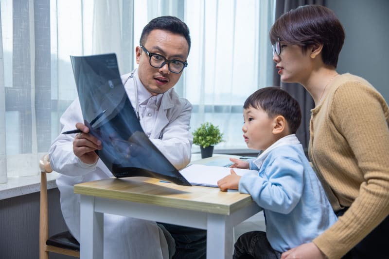 Doctor showing child's chest xray to mother and toddler son.