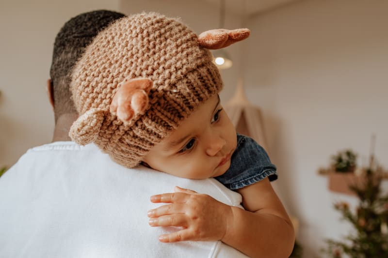 Young girl wearing soft knit hit while hugging her father.