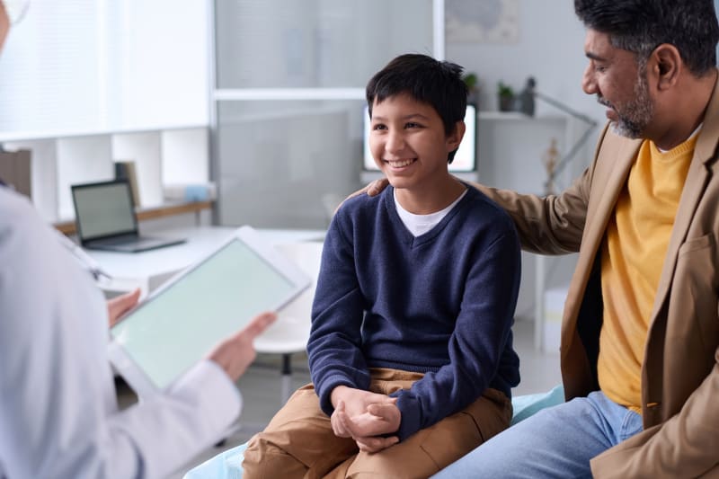 Doctor talking to parent and child at medical clinic.