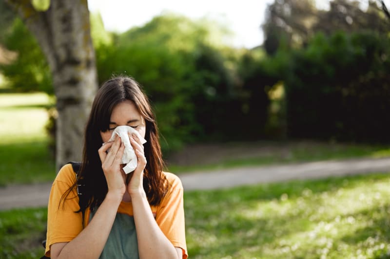 Female sneezing while outdoors.