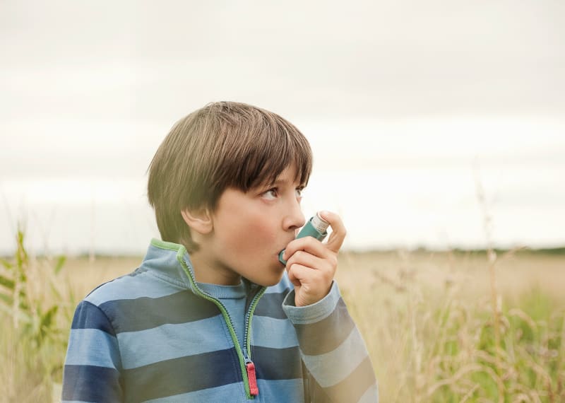 Young male using his inhaler outdoors.