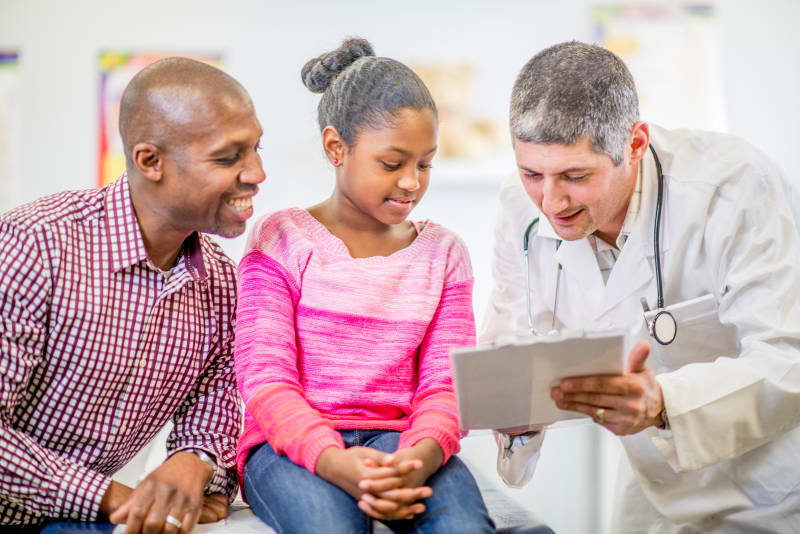 Doctor talking to parent and child at medical clinic.