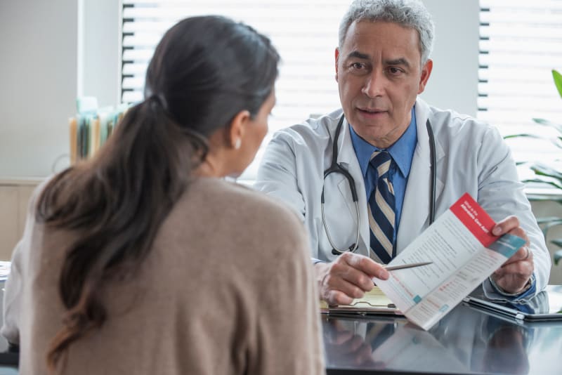 Doctor at clinic showing patient a brochure. 