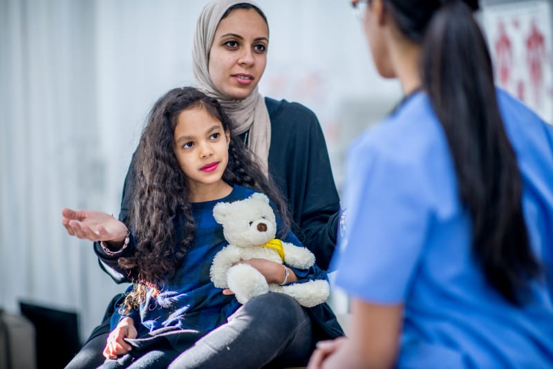 Mother speaking with Doctor with Child on her lap.