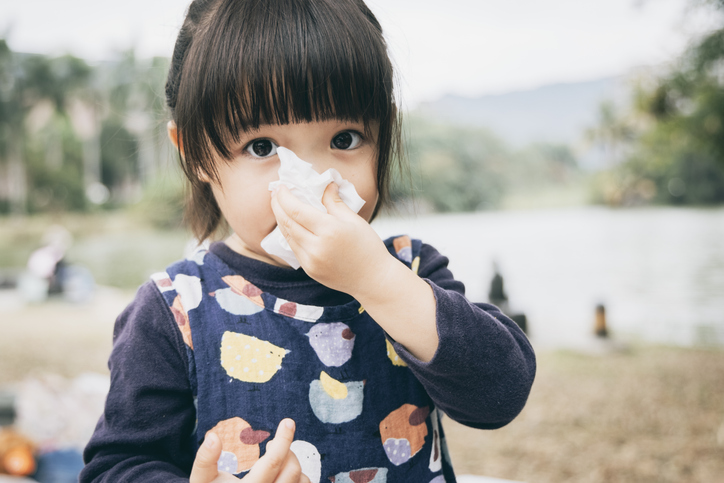 Child wiping their nose with a tissue