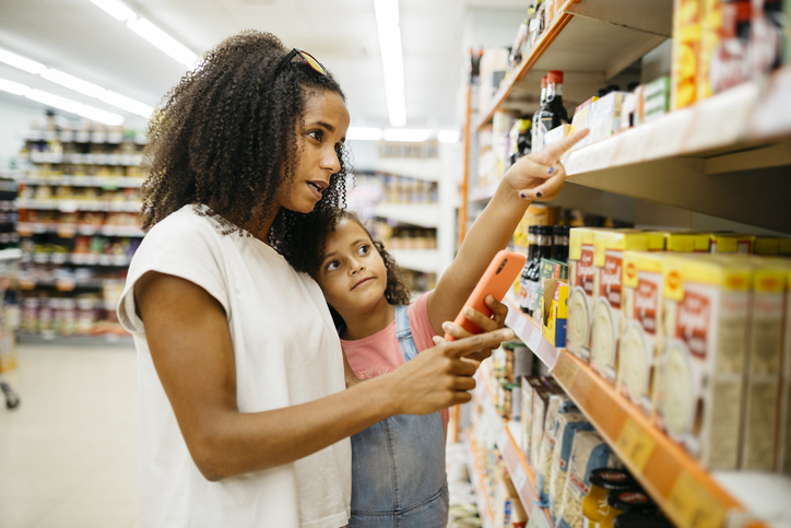 Mother and child checking food labels for allergies at the grocery store