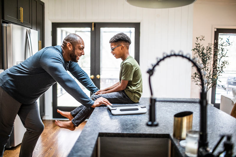 Father talking with tween son in residential kitchen.