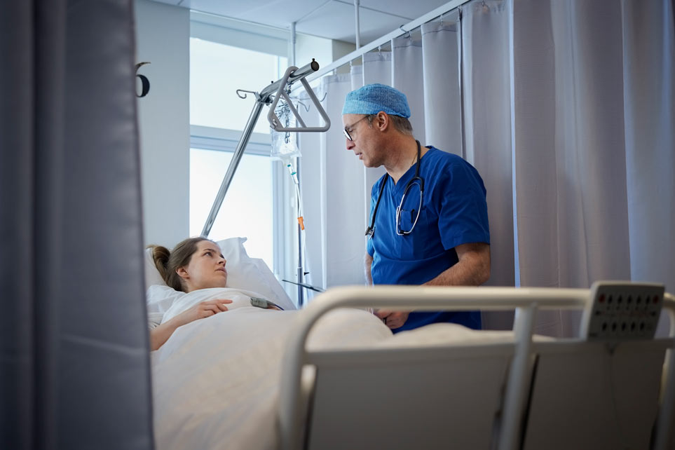 Male doctor examining patient on bed after surgery.