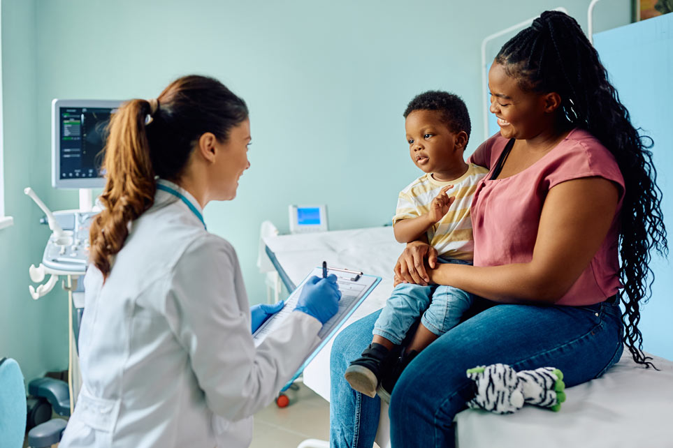 African American boy and his mother talking to female doctor at doctor's office.