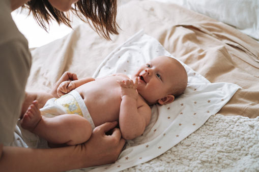 Mother leaning over infant laying on a blanket.