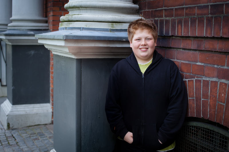 Overweight teenage boy in front of his school.