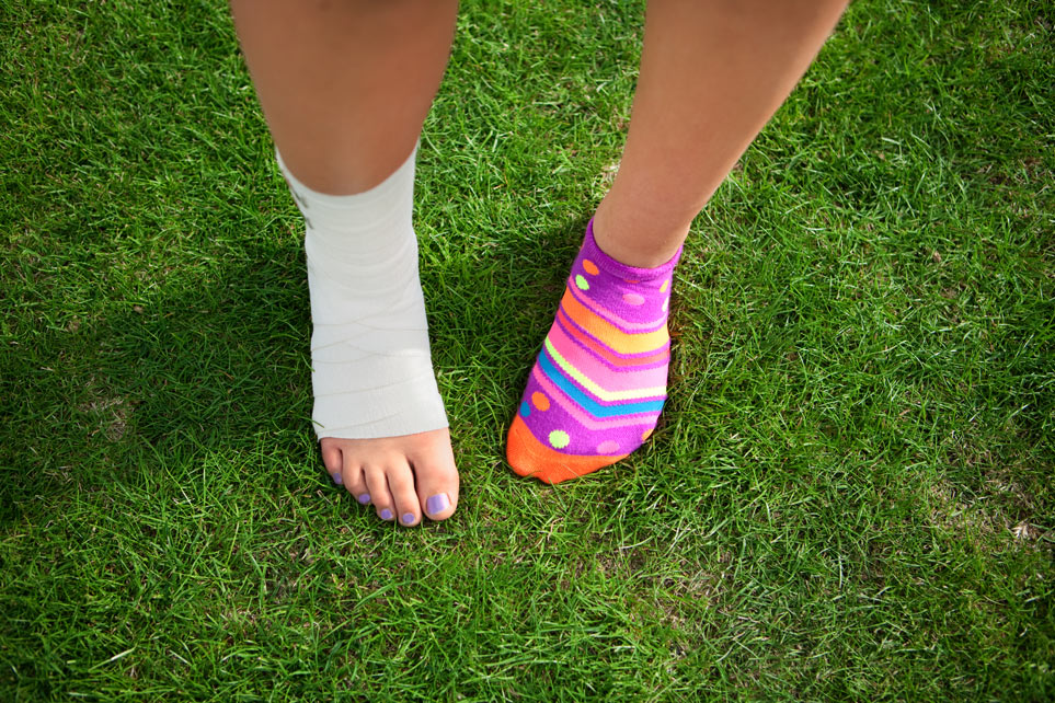 Closeup of girl's injured ankle wrapped with tape.