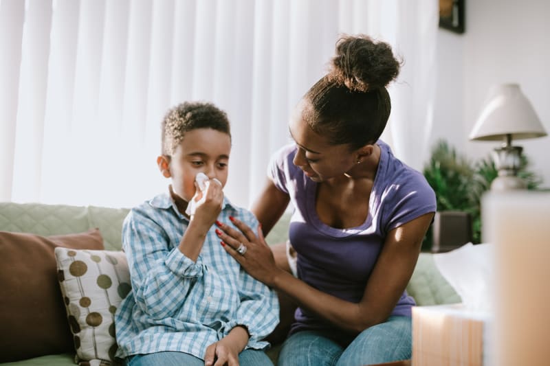 Young child with a cold blowing his nose.