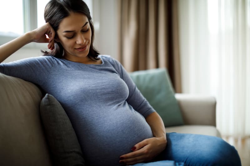 Pregnant woman sitting on a couch at home.