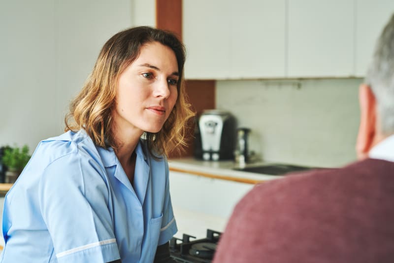 Female nurse sits with parent in home listening and providing comfort.