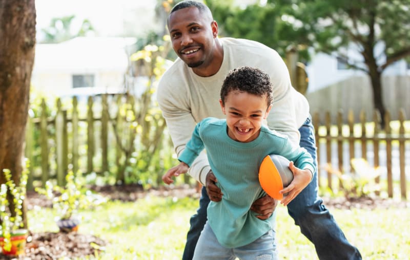 Father playing football with son in backyard. 