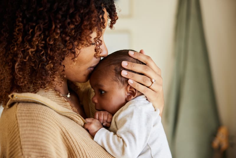 Mother kissing Baby's head and holding close.