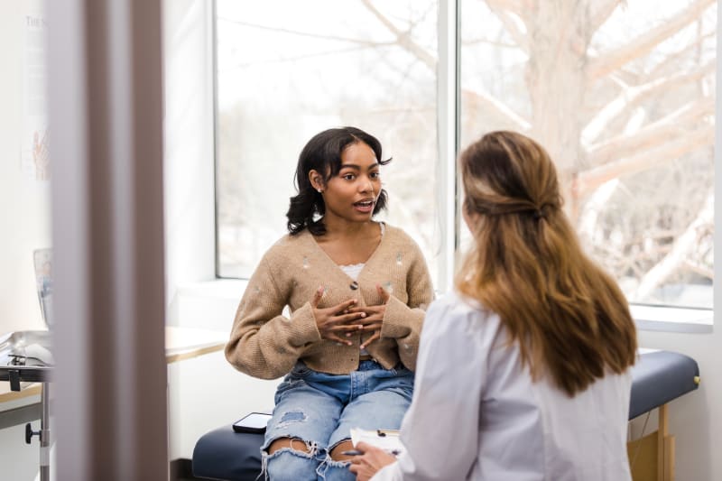 Young woman speaking with her doctor at a wellness exam. 