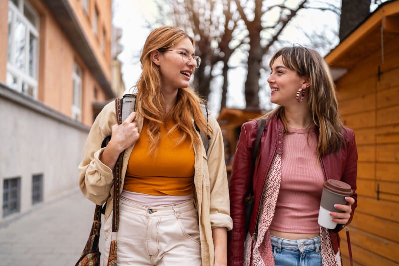 Two young women walking and talking outdoors. 