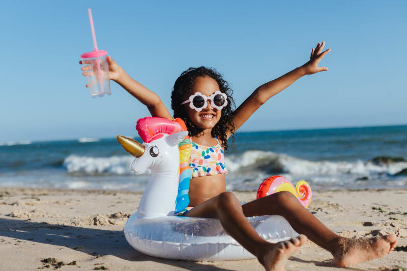 A young girl wearing sunglasses on a beach.