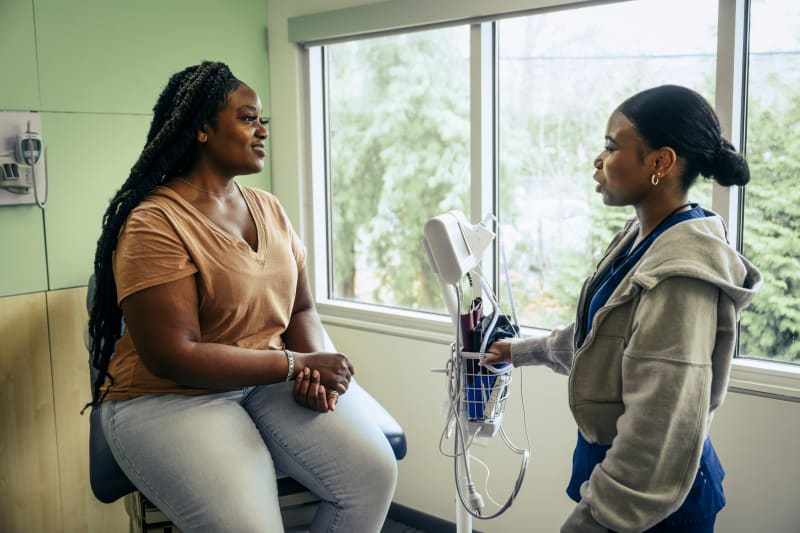 Young adult woman speaking to her doctor at wellness exam