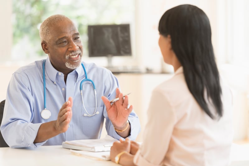 Male doctor talking to a woman in his office.