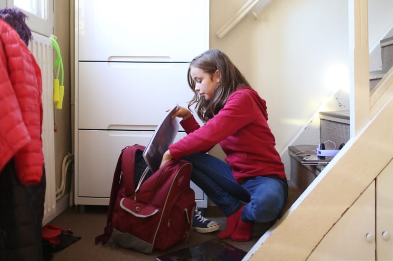 Young Girl loading her backpack for school.