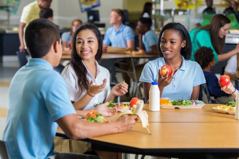 A group of teens eating a healthy lunch at school.