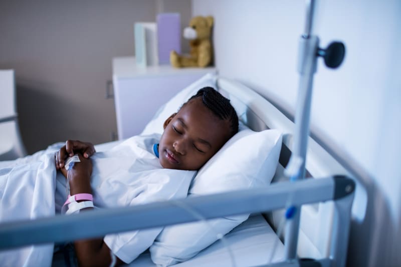 Young girl sleeping in hospital bed after surgery.
