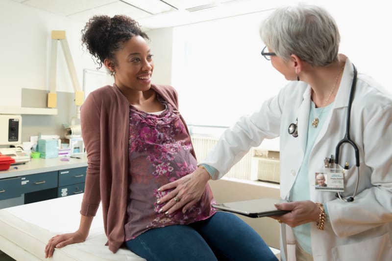 Pregnant patient talking with doctor at clinic.