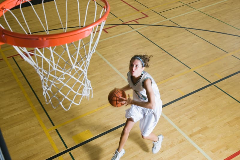 Teenage girl playing basketball. 