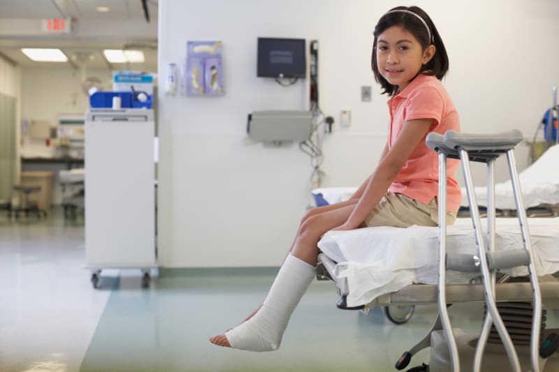 Young Girl with crutches in hospital bed. 