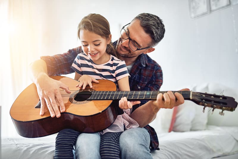 Child playing guitar with parent