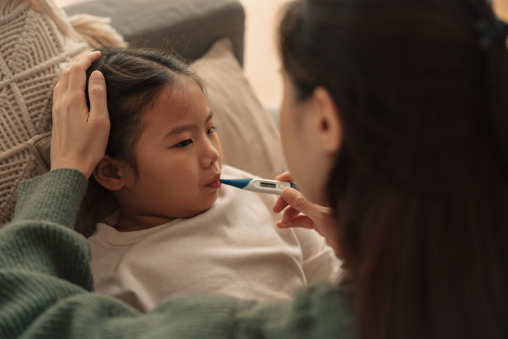 Child with thermometer and parent