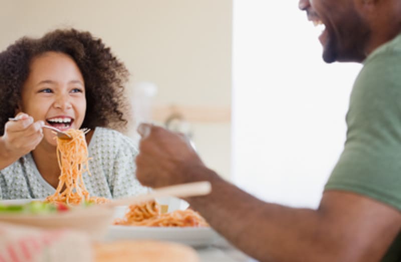 Young Daughter eating dinner with Father at the table.