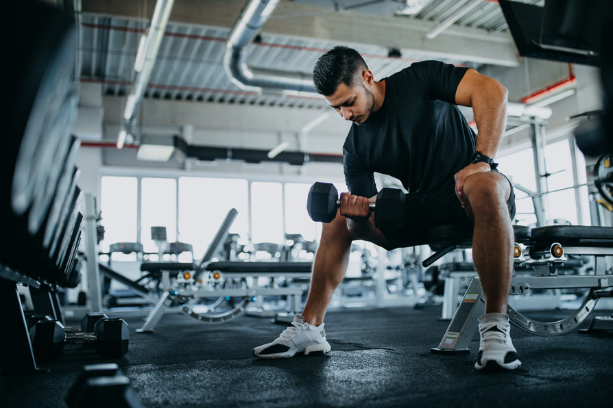 Young man lifting weights in gym